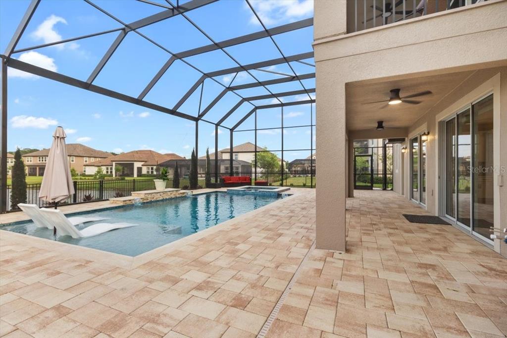A screened-in patio features a swimming pool with lounge chairs and paver flooring — 33239 KATELAND DRIVE, WESLEY CHAPEL, FL