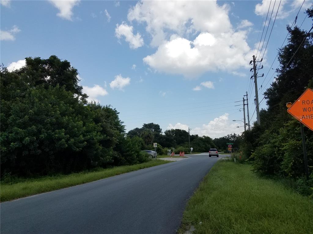 A paved road leads toward an intersection with a stop sign and construction signage — PATRICIA STREET, KISSIMMEE, FL