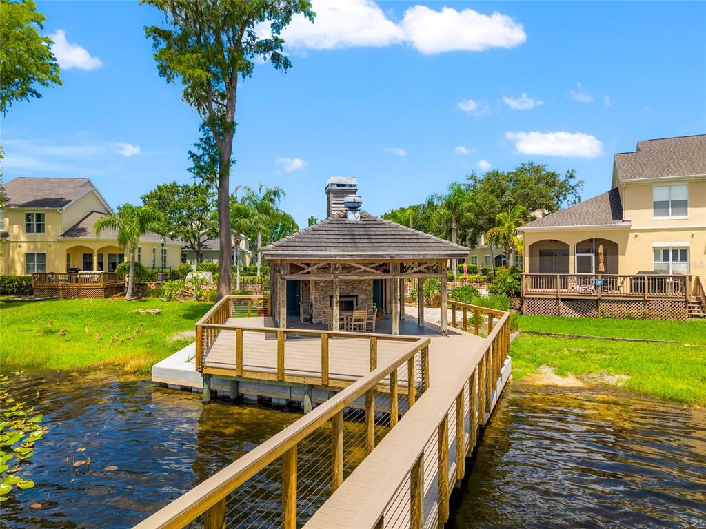 A wooden dock leads to a covered gazebo with a stone fireplace on a lake — 3519 HEARDS FERRY DRIVE, TAMPA, FL