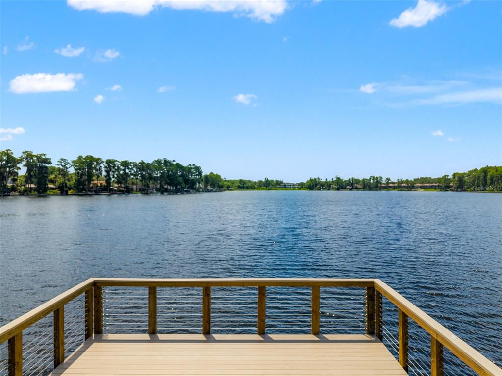 A wooden deck with cable railings overlooks a large lake under a blue sky — 3519 HEARDS FERRY DRIVE, TAMPA, FL