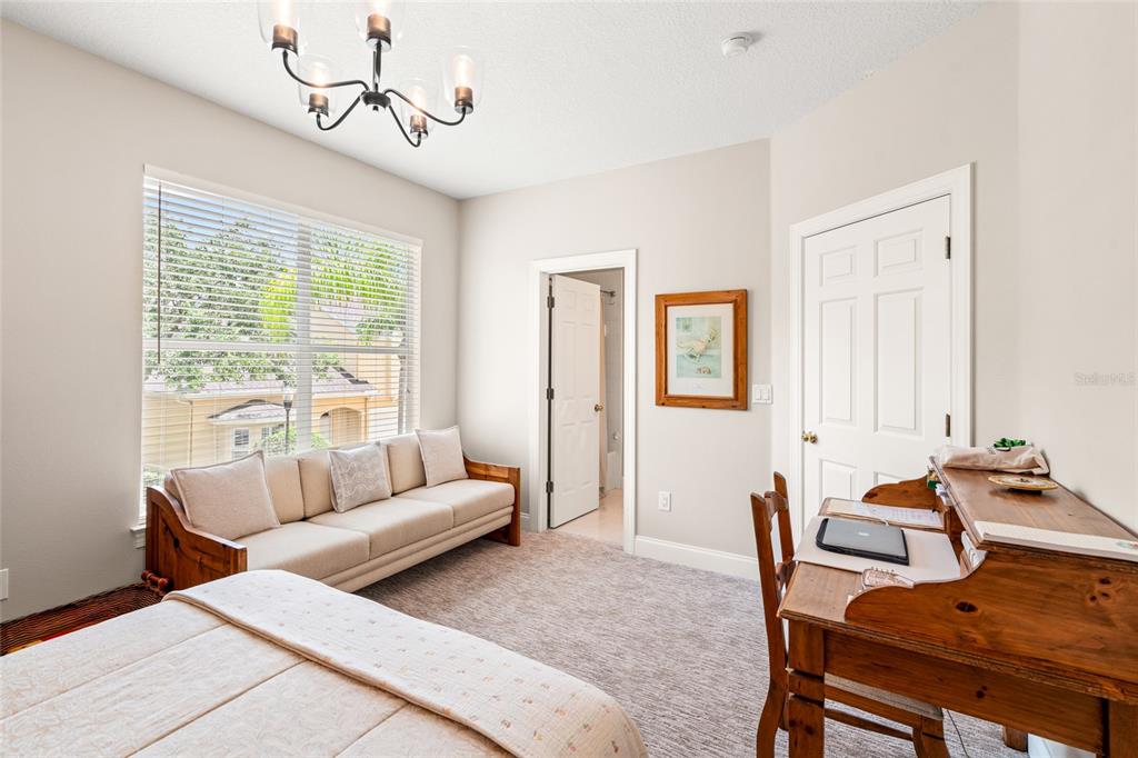 A bedroom features a sofa, a wooden desk, a chandelier, and a doorway to a bathroom — 3519 HEARDS FERRY DRIVE, TAMPA, FL