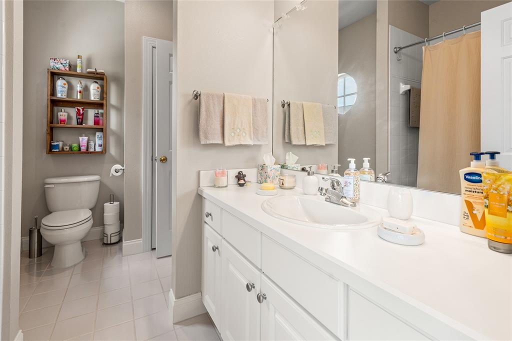 A bathroom features a white vanity, a toilet, a wall-mounted shelf, and a shower curtain — 3519 HEARDS FERRY DRIVE, TAMPA, FL