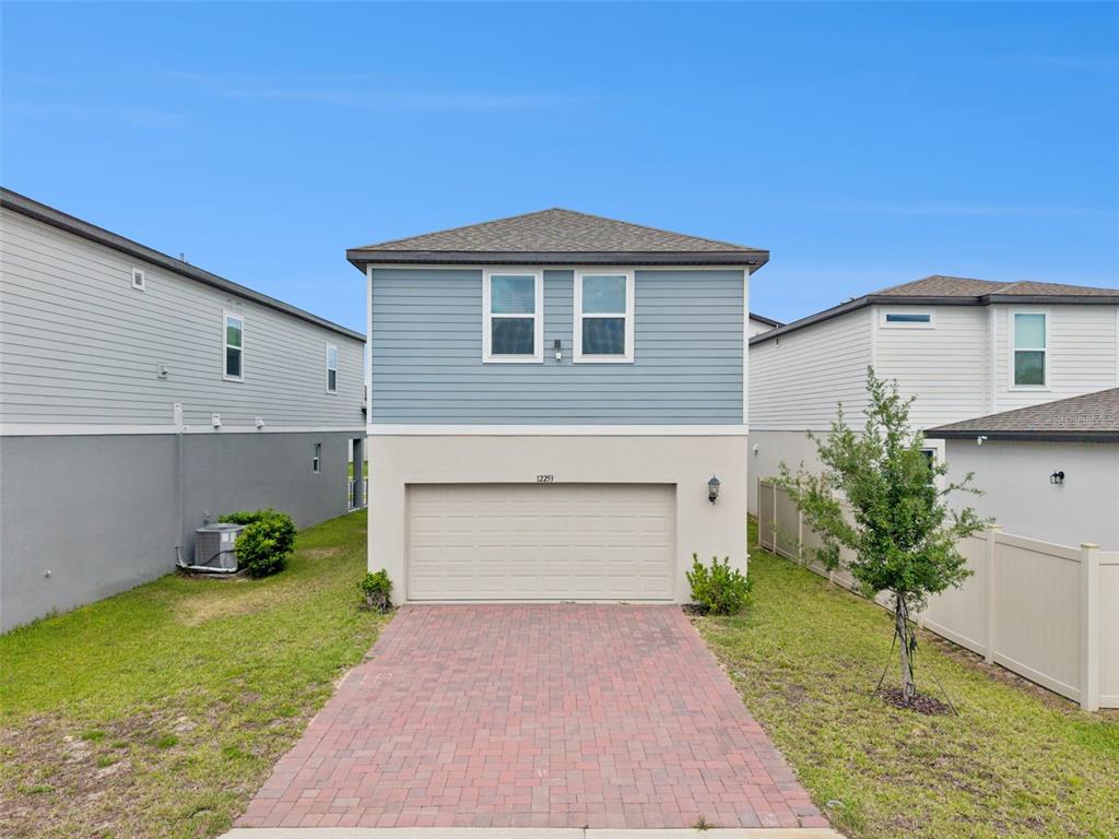 A two-story house with a blue-sided upper level, a beige garage, and a brick driveway — 12253 S BRACCO STREET, WINTER GARDEN, FL