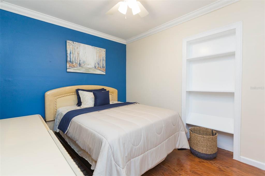 A bedroom features a blue accent wall, a bed with neutral bedding, and built-in shelving — 2504 E 12TH AVENUE, TAMPA, FL