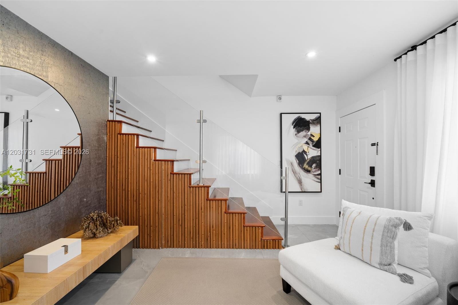 An entryway features a wooden staircase with glass railings, a round mirror, and white furniture — 2752 SW 11th St, Miami FL 33135, MIAMI, FL