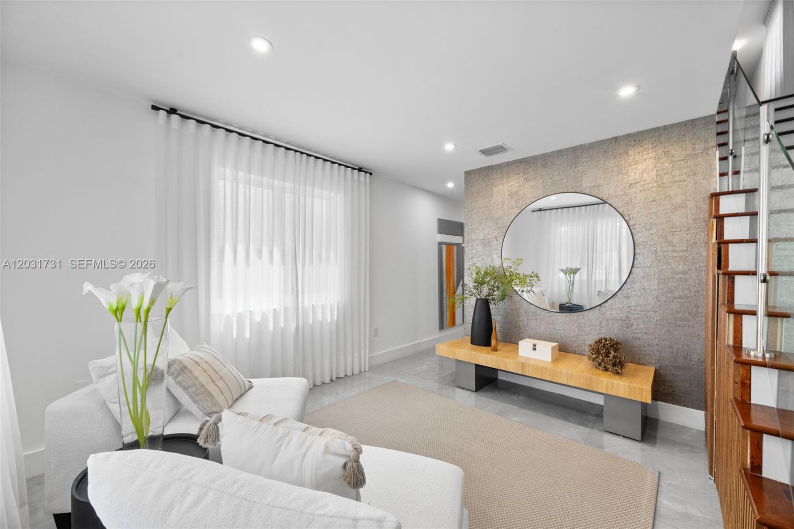A modern living room features a textured accent wall, circular mirror, and wooden bench — 2752 SW 11th St, Miami FL 33135, MIAMI, FL