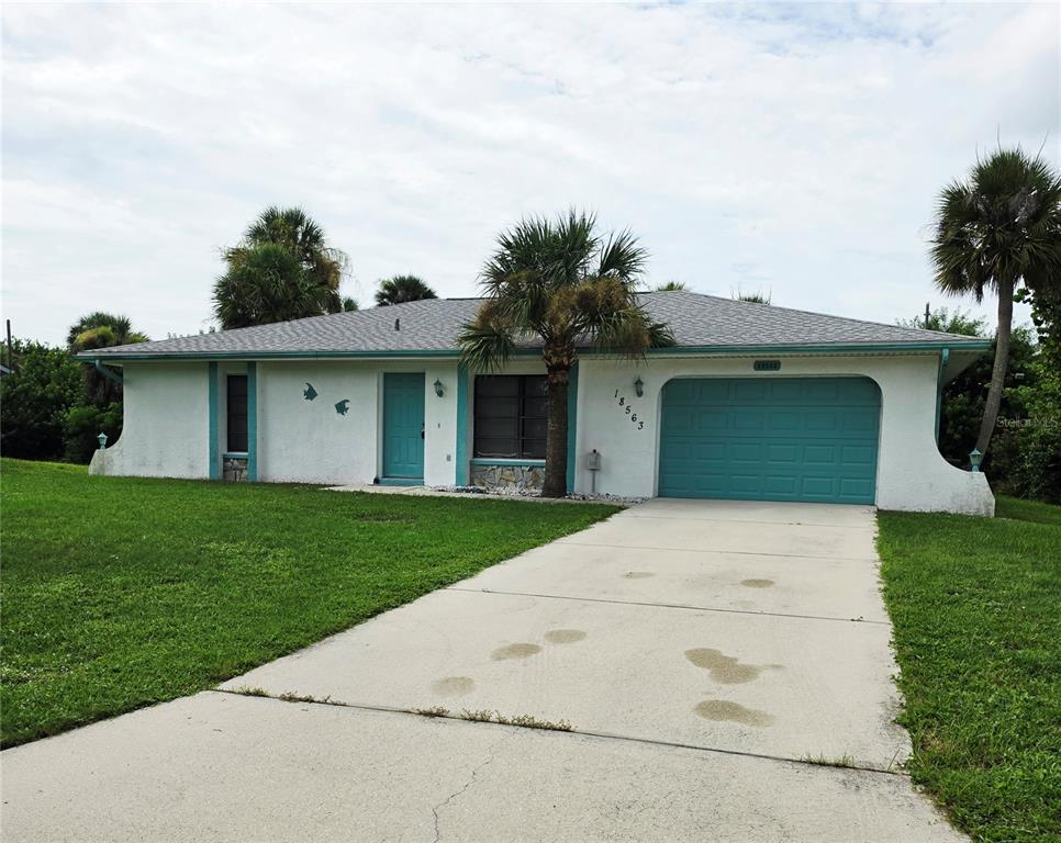 A single-story white house with a teal garage door and front door sits on a lawn — 18563 FORT SMITH CIRCLE, PORT CHARLOTTE, FL