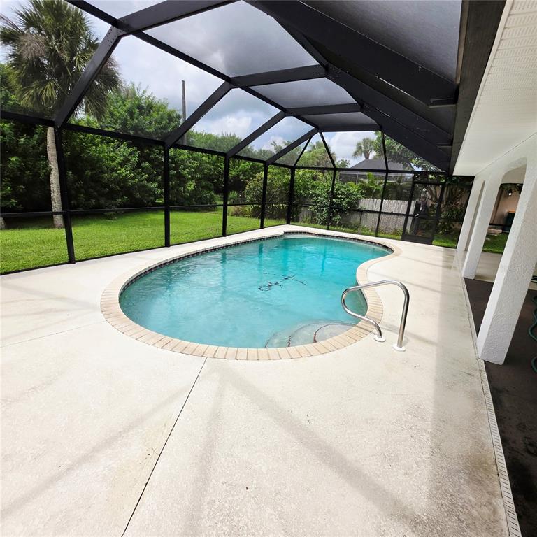 A kidney-shaped swimming pool sits on a concrete patio enclosed by a black screen cage — 18563 FORT SMITH CIRCLE, PORT CHARLOTTE, FL