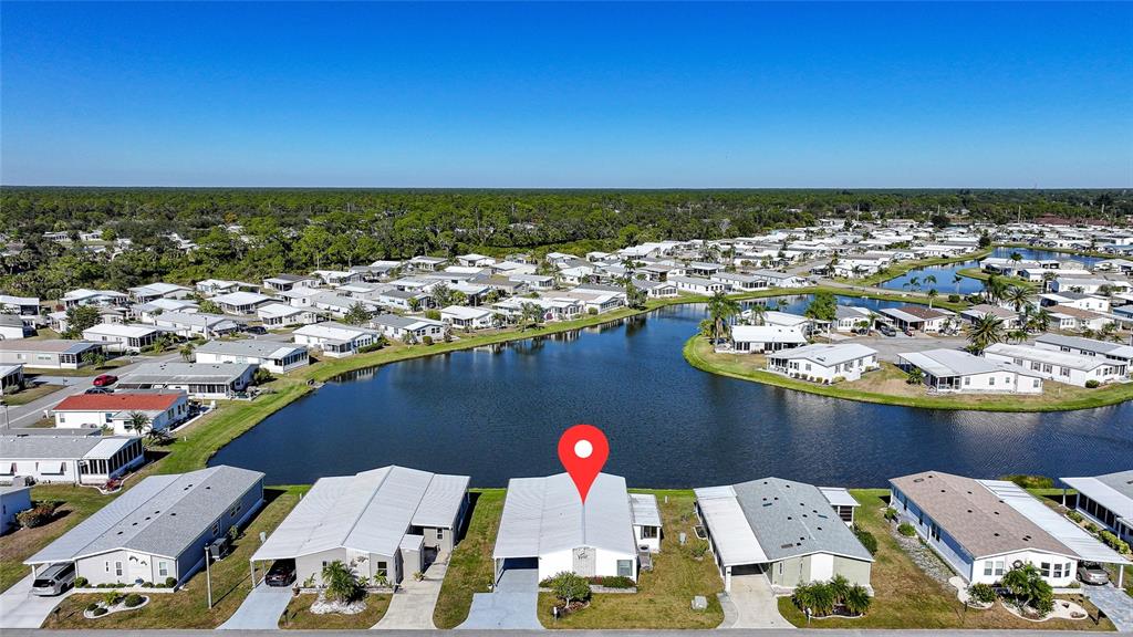 An aerial view shows a row of manufactured homes bordering a lake in a community — 495 SCHOONER STREET, NORTH PORT, FL