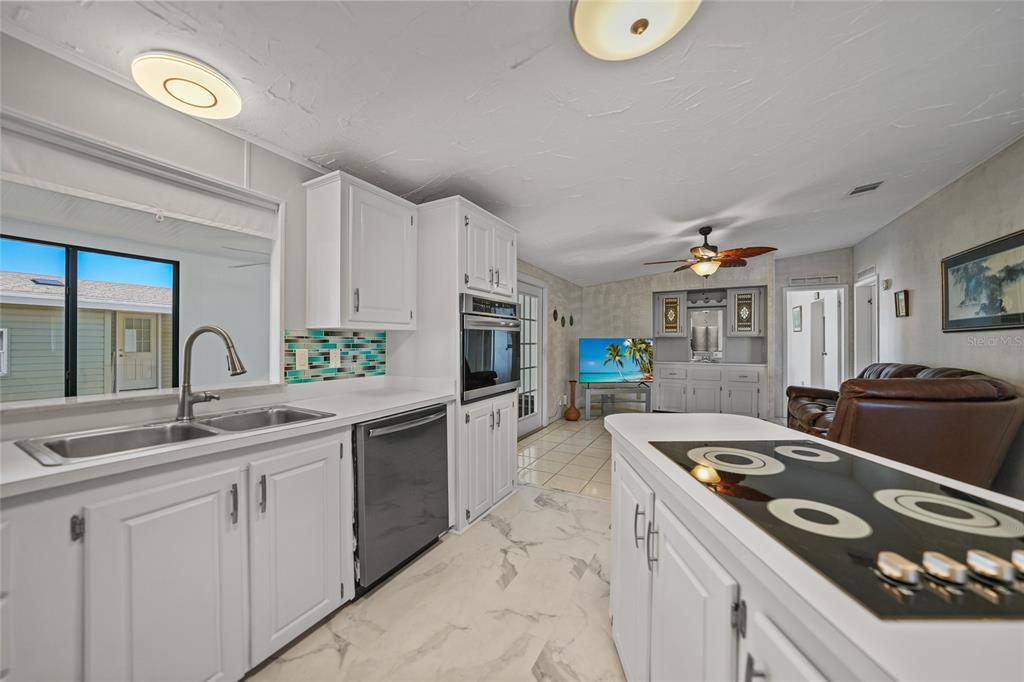 A kitchen with white cabinets, a center island, and stainless steel appliances opens to a living area — 495 SCHOONER STREET, NORTH PORT, FL