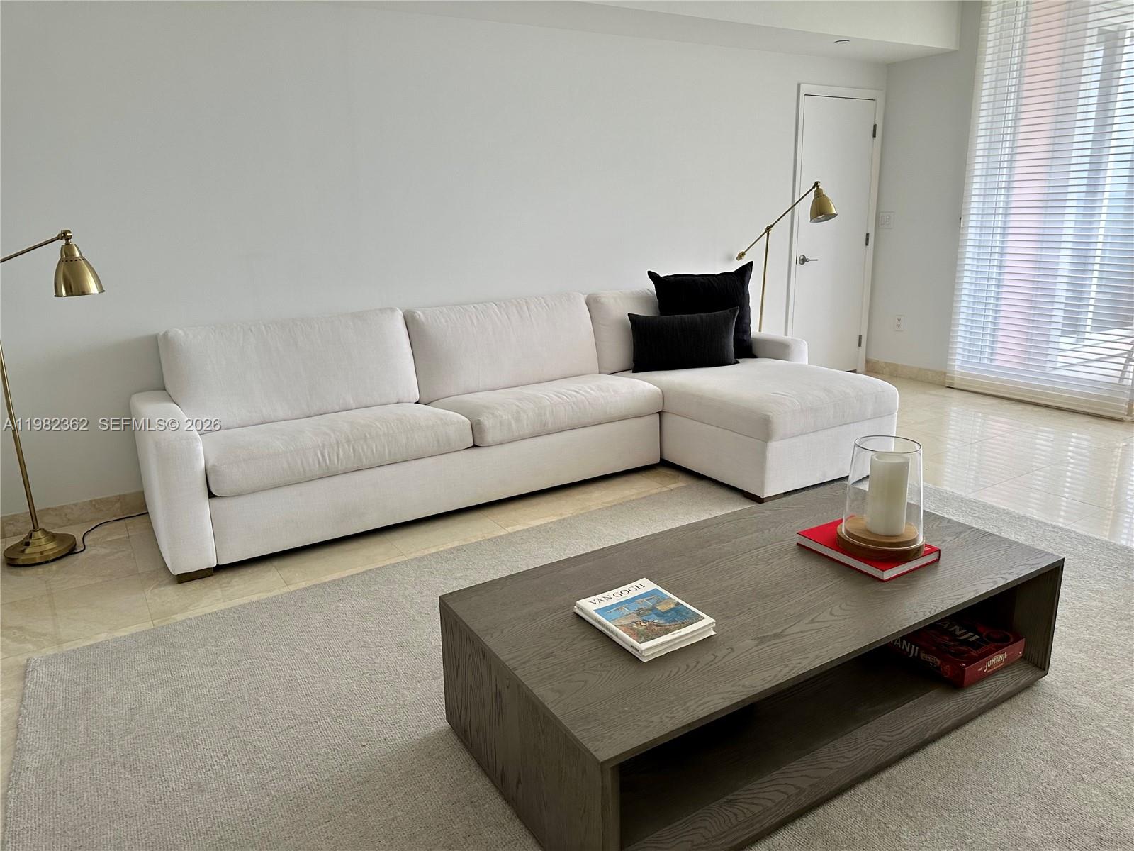 A living room features a white sectional sofa, a wooden coffee table, and two floor lamps — 785 Crandon Blvd # 803, Key Biscayne FL 33149, KEY BISCAYNE, FL