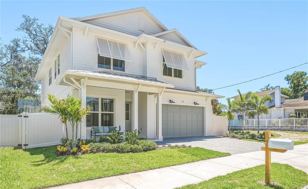 A two-story white house with a gray garage and a front porch under a blue sky — 814 W AMELIA AVENUE, TAMPA, FL