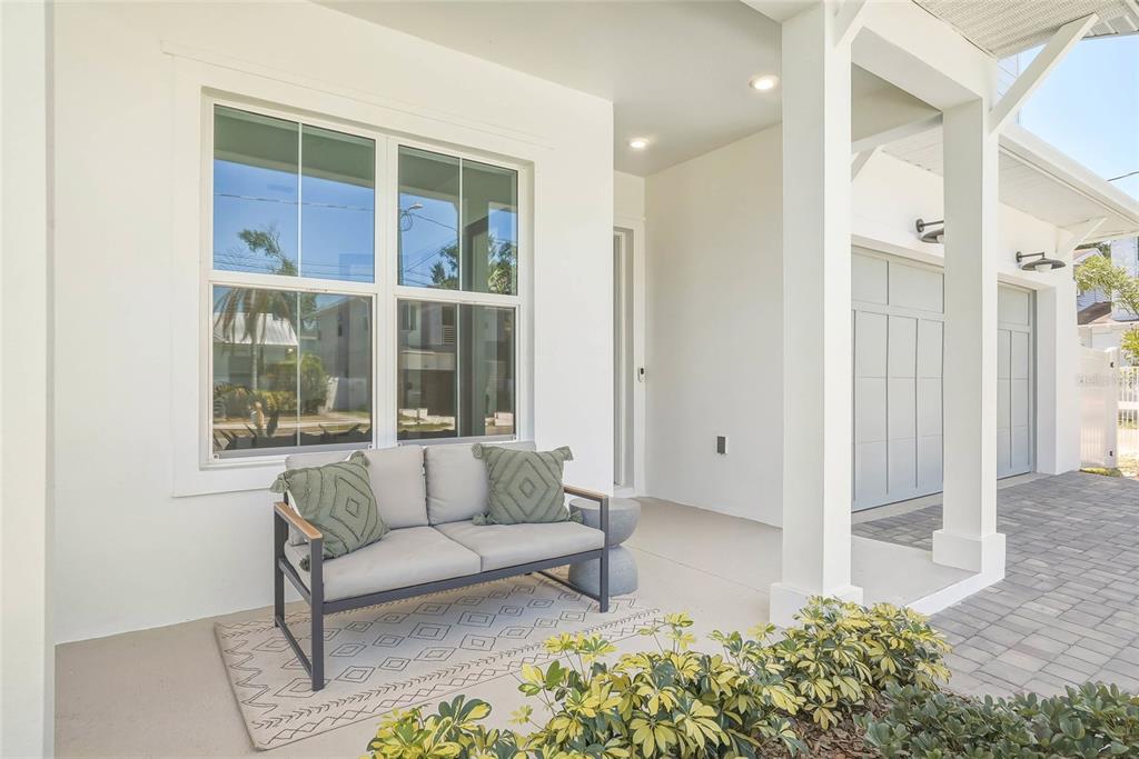 A covered front porch features a gray loveseat on a patterned rug near white columns — 814 W AMELIA AVENUE, TAMPA, FL