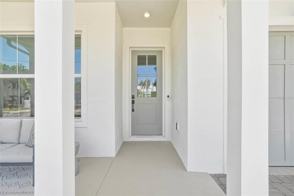 A covered porch features a light gray front door with glass panels and white walls — 814 W AMELIA AVENUE, TAMPA, FL