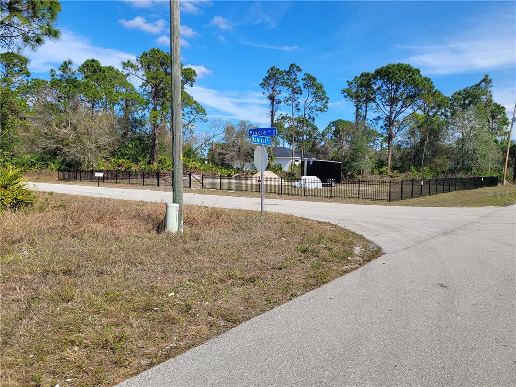 A fenced vacant lot sits at the corner of two paved streets with street signs — 236 PINOLA AVENUE S, LEHIGH ACRES, FL