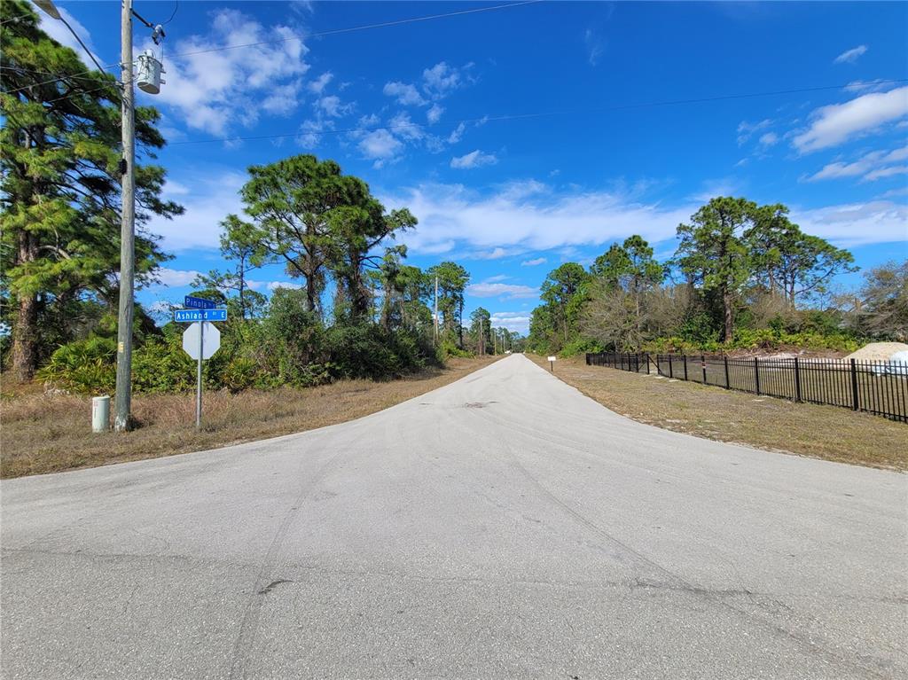 An asphalt road stretches into the distance at an intersection with street signs — 236 PINOLA AVENUE S, LEHIGH ACRES, FL