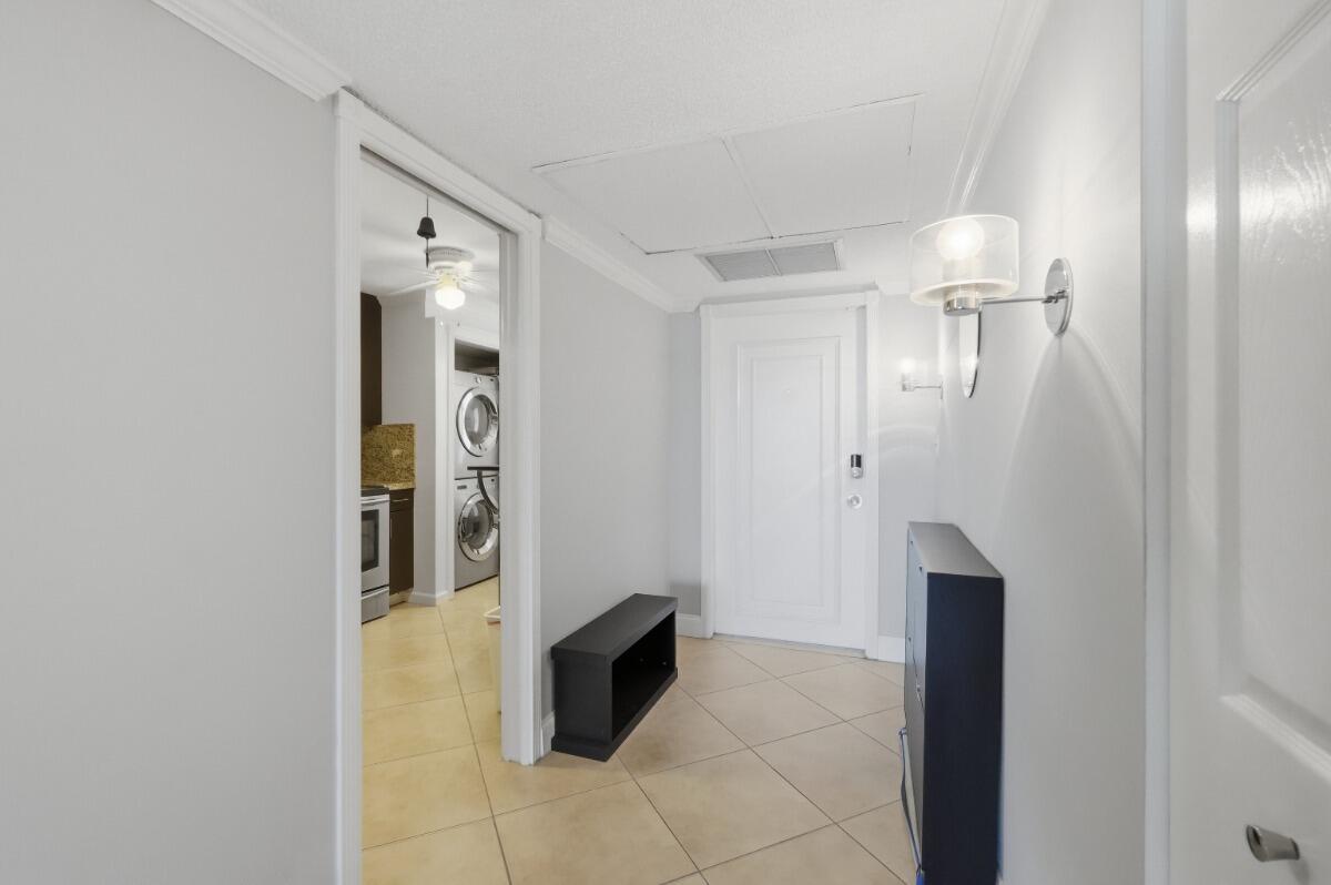 A tiled entryway features a white door, a wall sconce, and a view into a kitchen — 3001 S Palm Aire Drive # 206, Pompano Beach FL 33069, POMPANO BEACH, FL