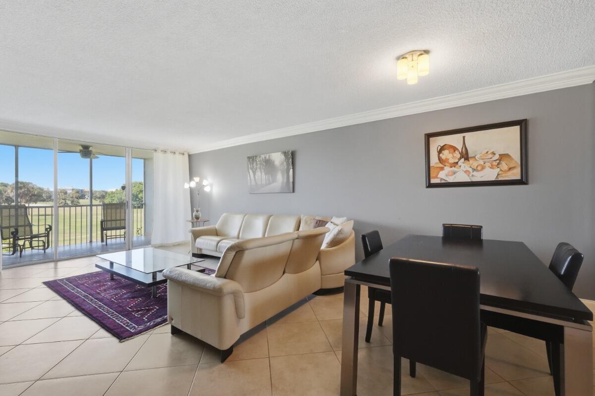 A living and dining area with tile floors, a white sectional sofa, and a balcony view — 3001 S Palm Aire Drive # 206, Pompano Beach FL 33069, POMPANO BEACH, FL