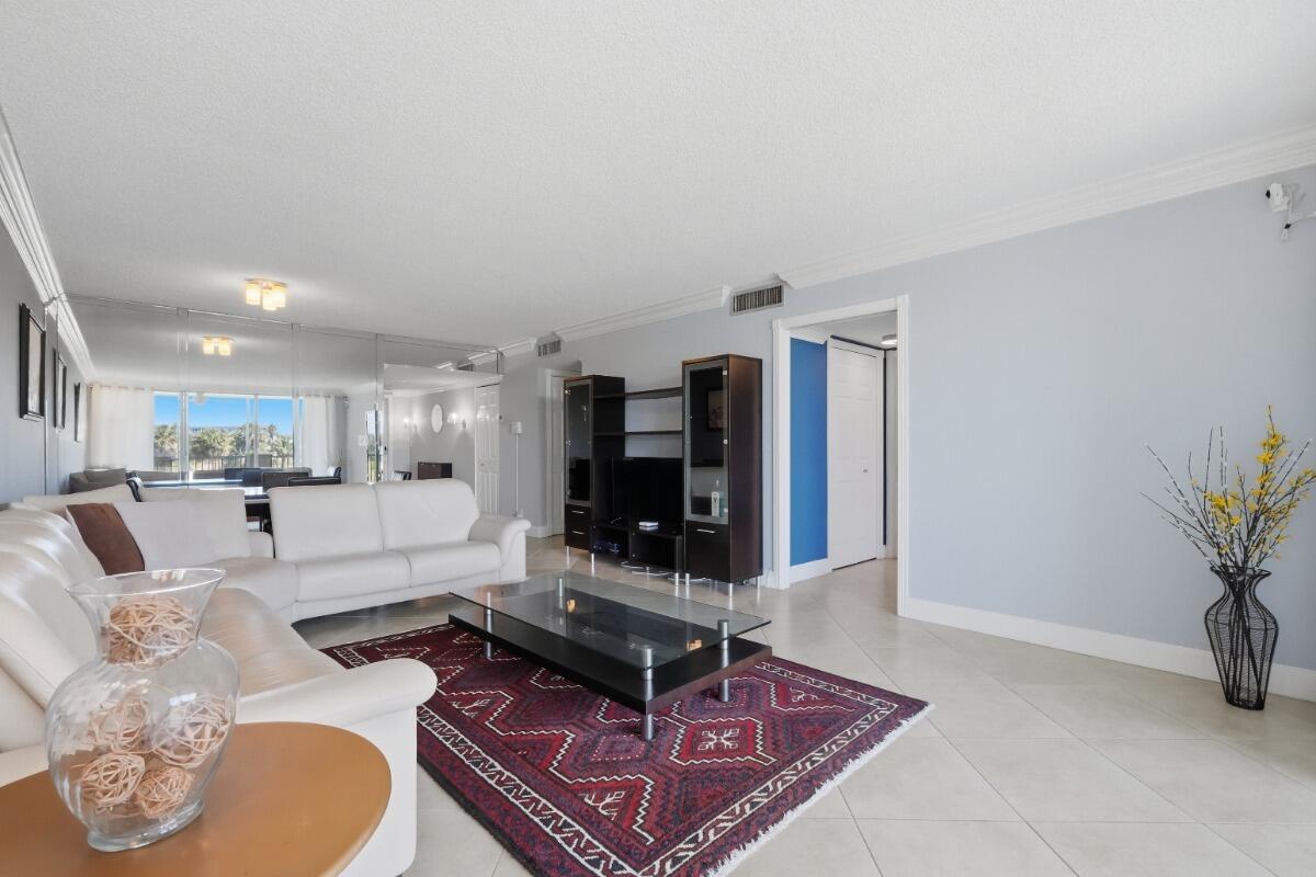 A living room features white tile floors, a white leather sofa, and a patterned area rug — 3001 S Palm Aire Drive # 206, Pompano Beach FL 33069, POMPANO BEACH, FL