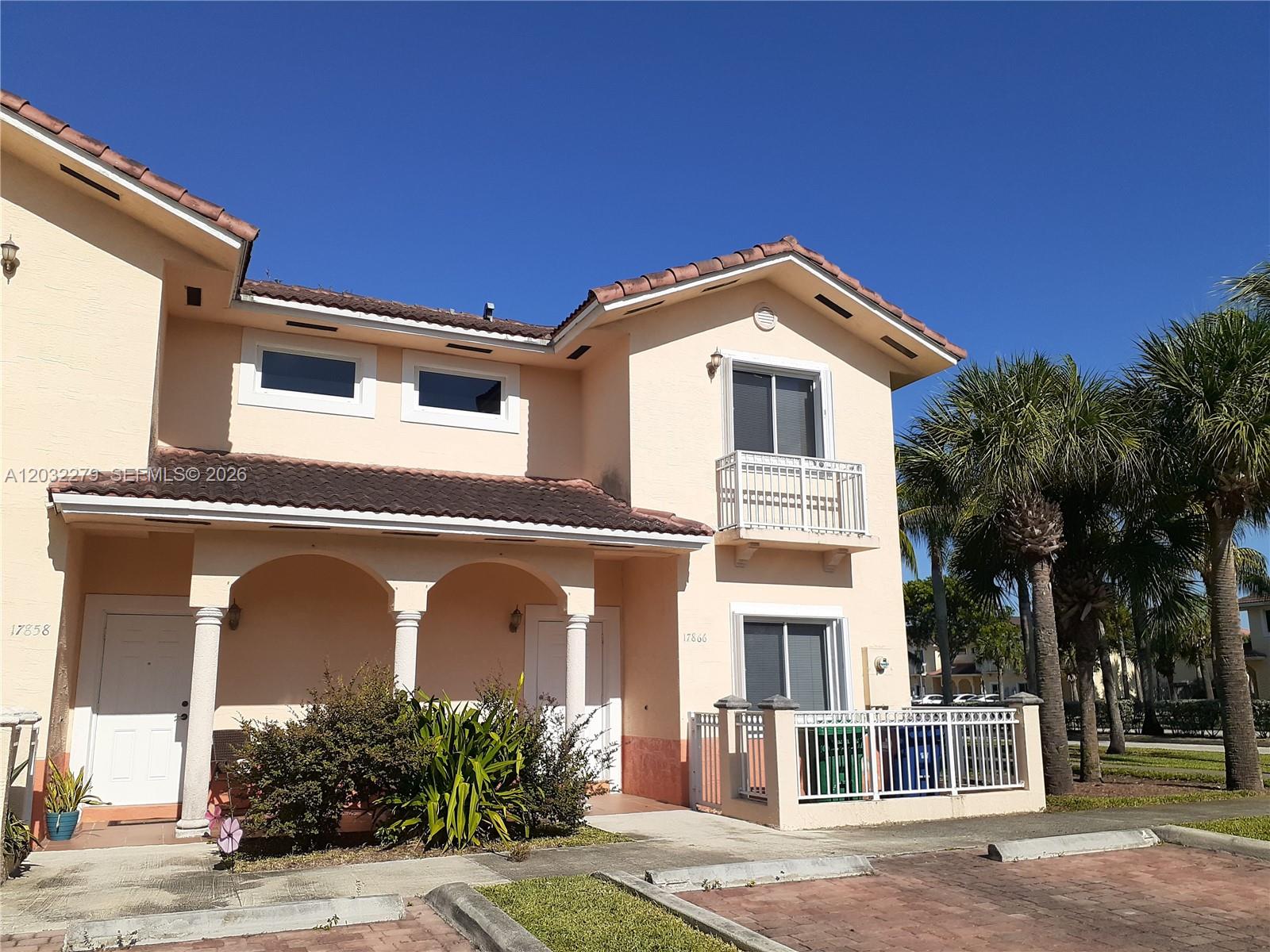 A two-story peach-colored townhouse features a tiled roof, arched entryway, and a small balcony — 17866 NW 74th Ct, Hialeah FL 33015, HIALEAH, FL