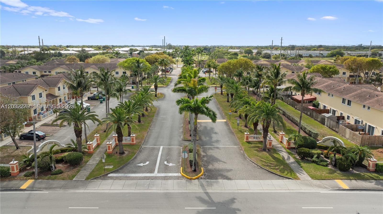 An aerial view shows the entrance to a residential complex with palm trees and buildings — 17866 NW 74th Ct, Hialeah FL 33015, HIALEAH, FL