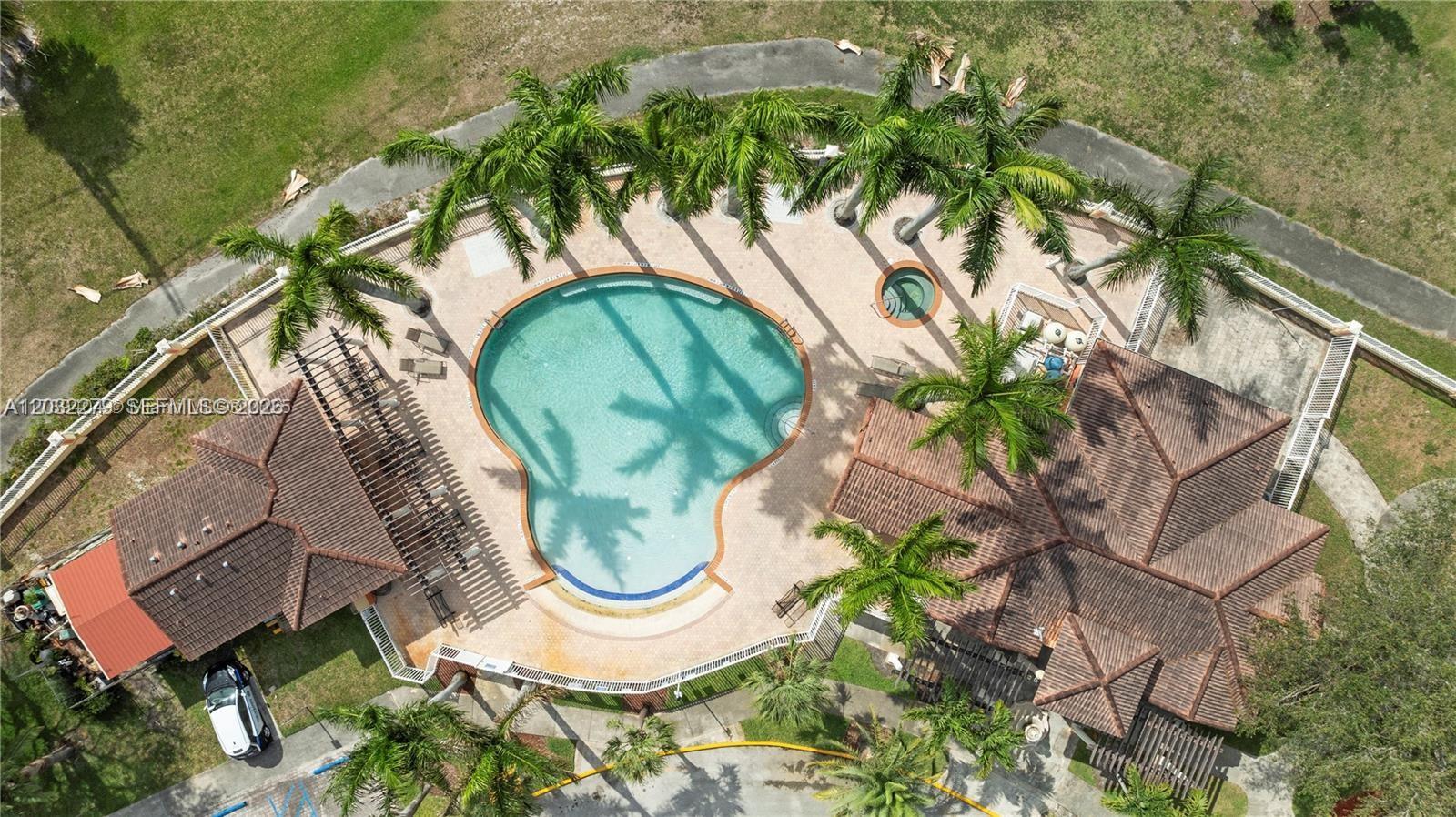 An aerial view shows a swimming pool and hot tub surrounded by palm trees and buildings — 17866 NW 74th Ct, Hialeah FL 33015, HIALEAH, FL