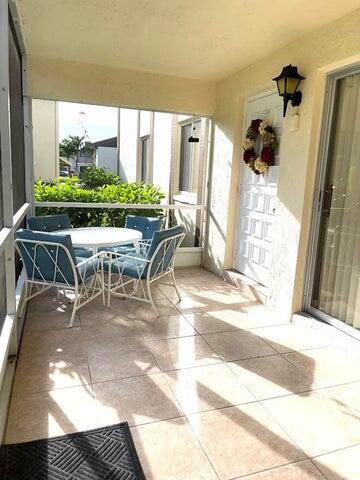A screened-in patio features tiled flooring, a small round table with four chairs, and a door — 5839 La Pinata Boulevard, FL 33463, FL