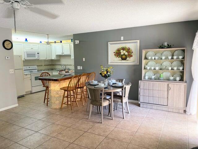 A kitchen with a breakfast bar and dining area featuring tile floors and light cabinetry — 5839 La Pinata Boulevard, FL 33463, FL