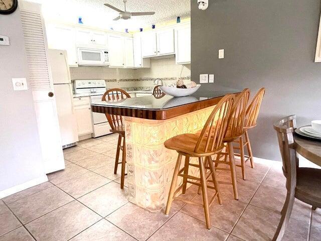 A kitchen features a glass-topped bar with a glass block base and wooden stools — 5839 La Pinata Boulevard, FL 33463, FL