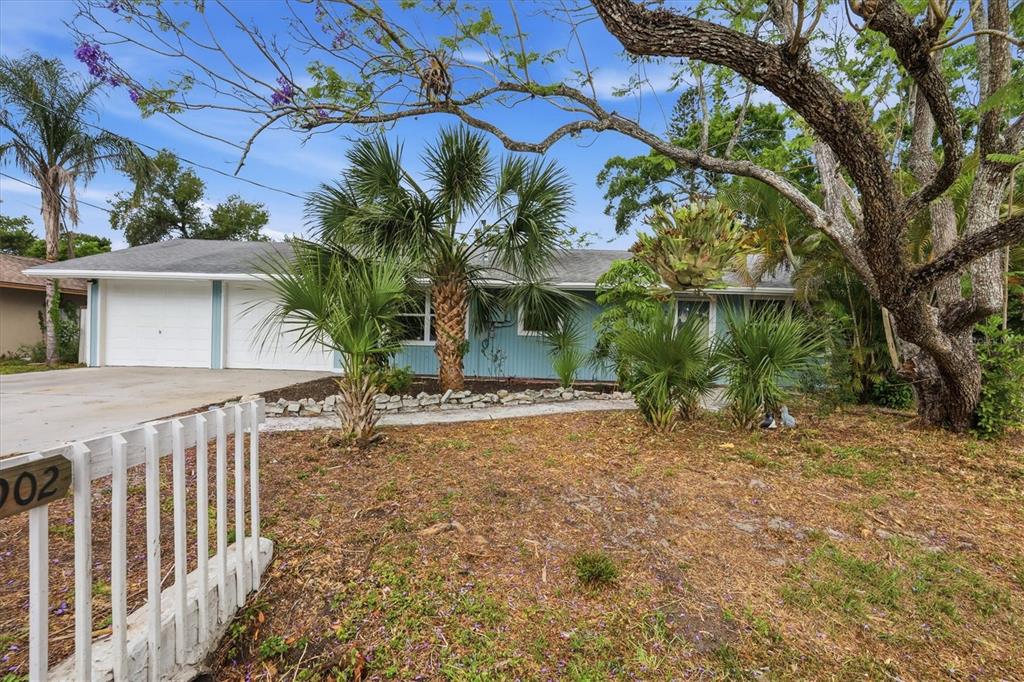 A single-story blue house with a two-car garage and palm trees in the front yard — 902 37TH STREET W, BRADENTON, FL