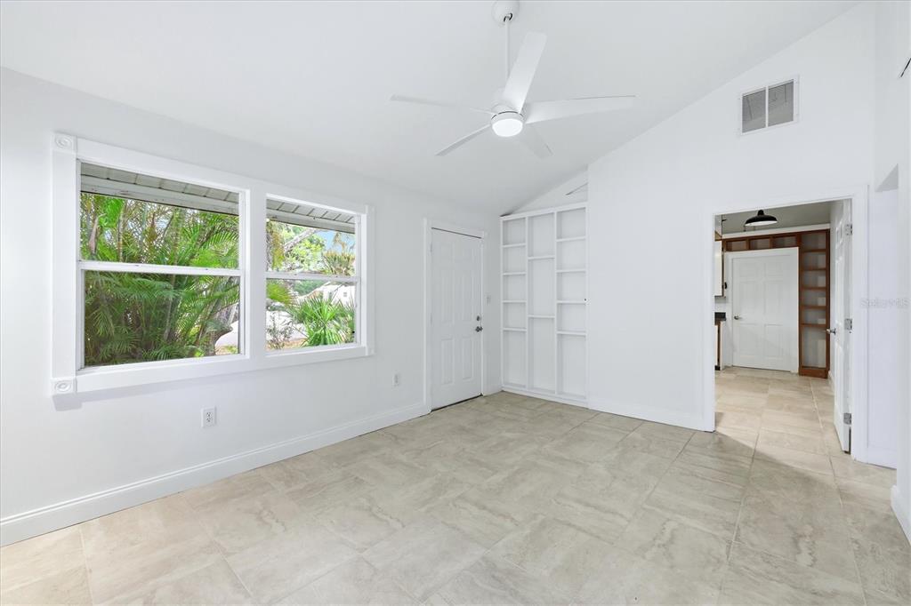 A bright room with white walls, tile flooring, a ceiling fan, and built-in shelving — 902 37TH STREET W, BRADENTON, FL