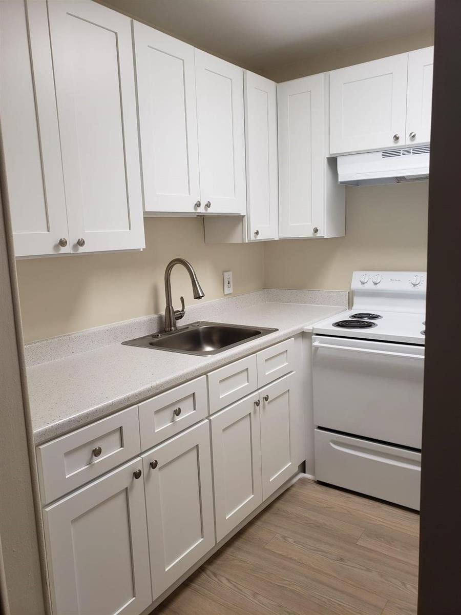 A small kitchen features white cabinets, a stainless steel sink, and a white electric stove — 146 Canterbury # 146, West Palm Beach FL 33417, WEST PALM BEACH, FL