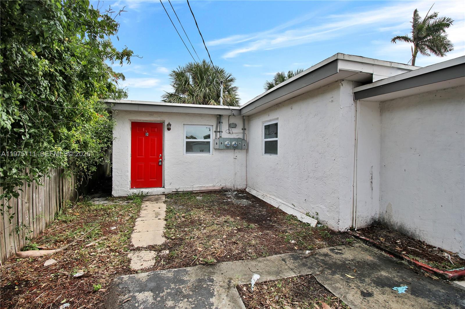 An exterior view of a white stucco building with a red door and electrical meters — 1160 W 26 th  ct, Riviera Beach FL 33404, RIVIERA BEACH, FL