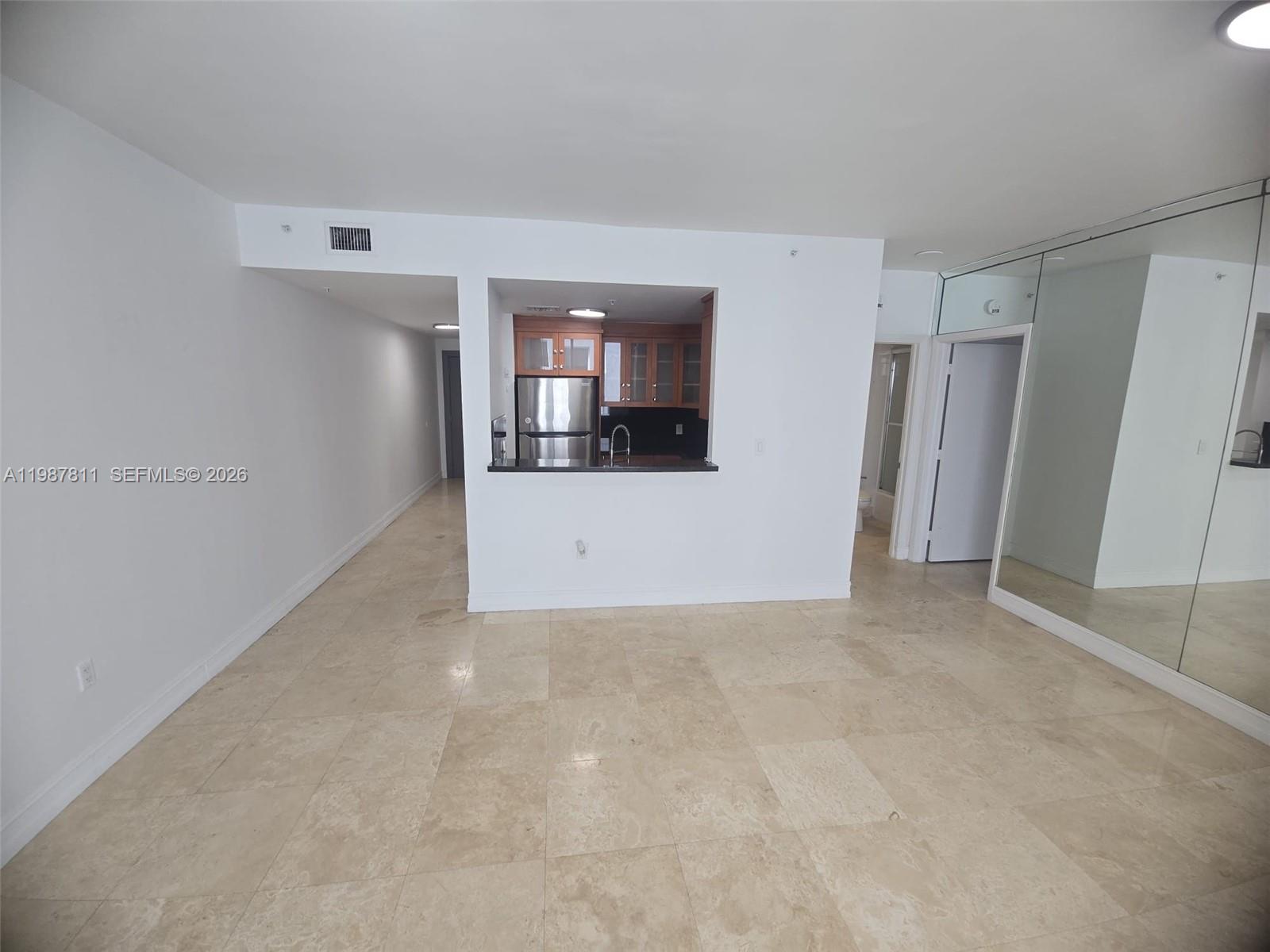 An open-concept living area features light tile flooring, a kitchen pass-through, and mirrored walls — 185 SE 14th Ter # 2701, Miami FL 33131, MIAMI, FL