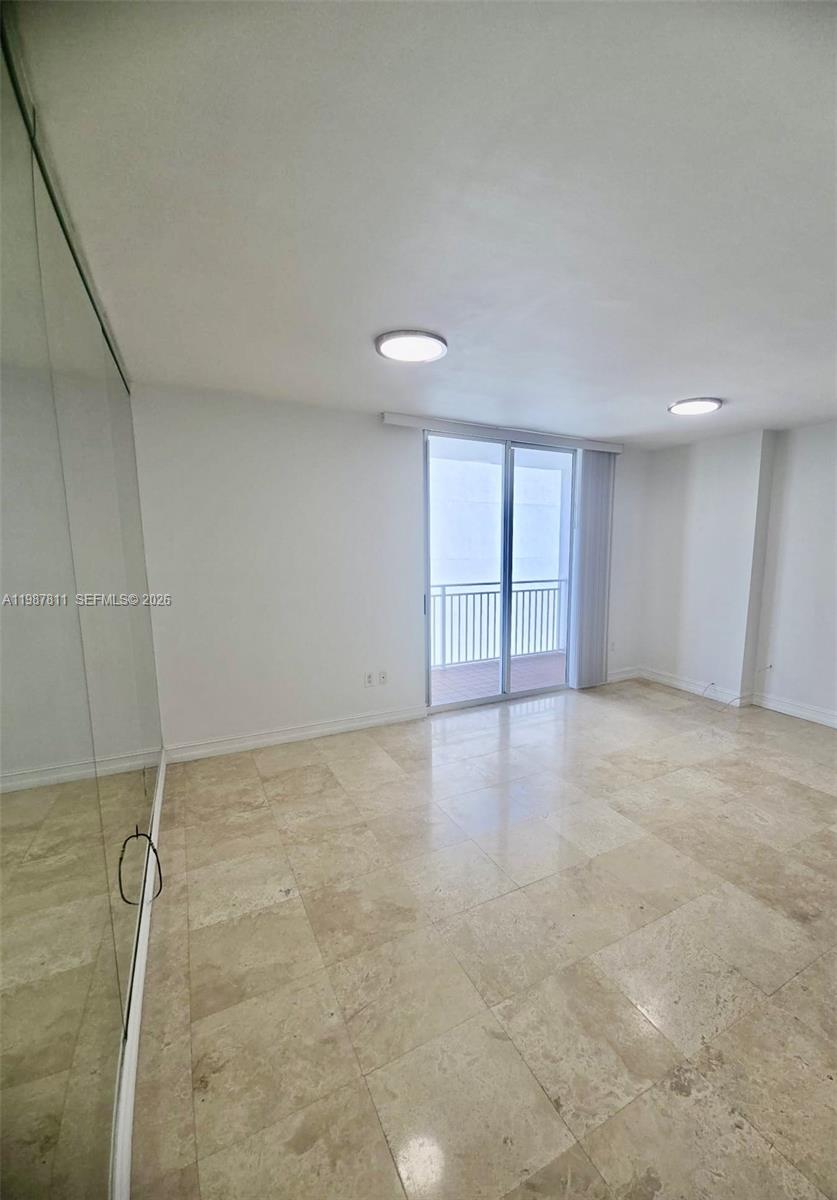 An empty room features light-colored tile flooring, white walls, recessed lighting, and a sliding glass door — 185 SE 14th Ter # 2701, Miami FL 33131, MIAMI, FL
