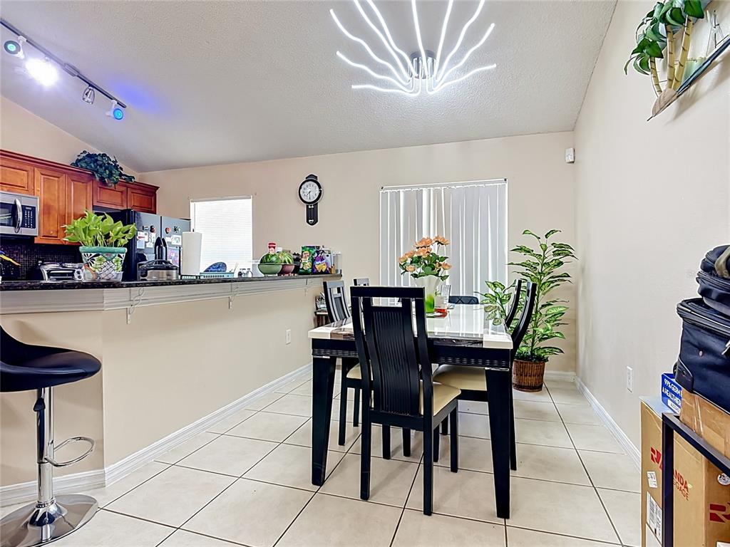 A dining area with a dark table and chairs sits adjacent to a kitchen counter — 1036 DUDLEY DRIVE, KISSIMMEE, FL