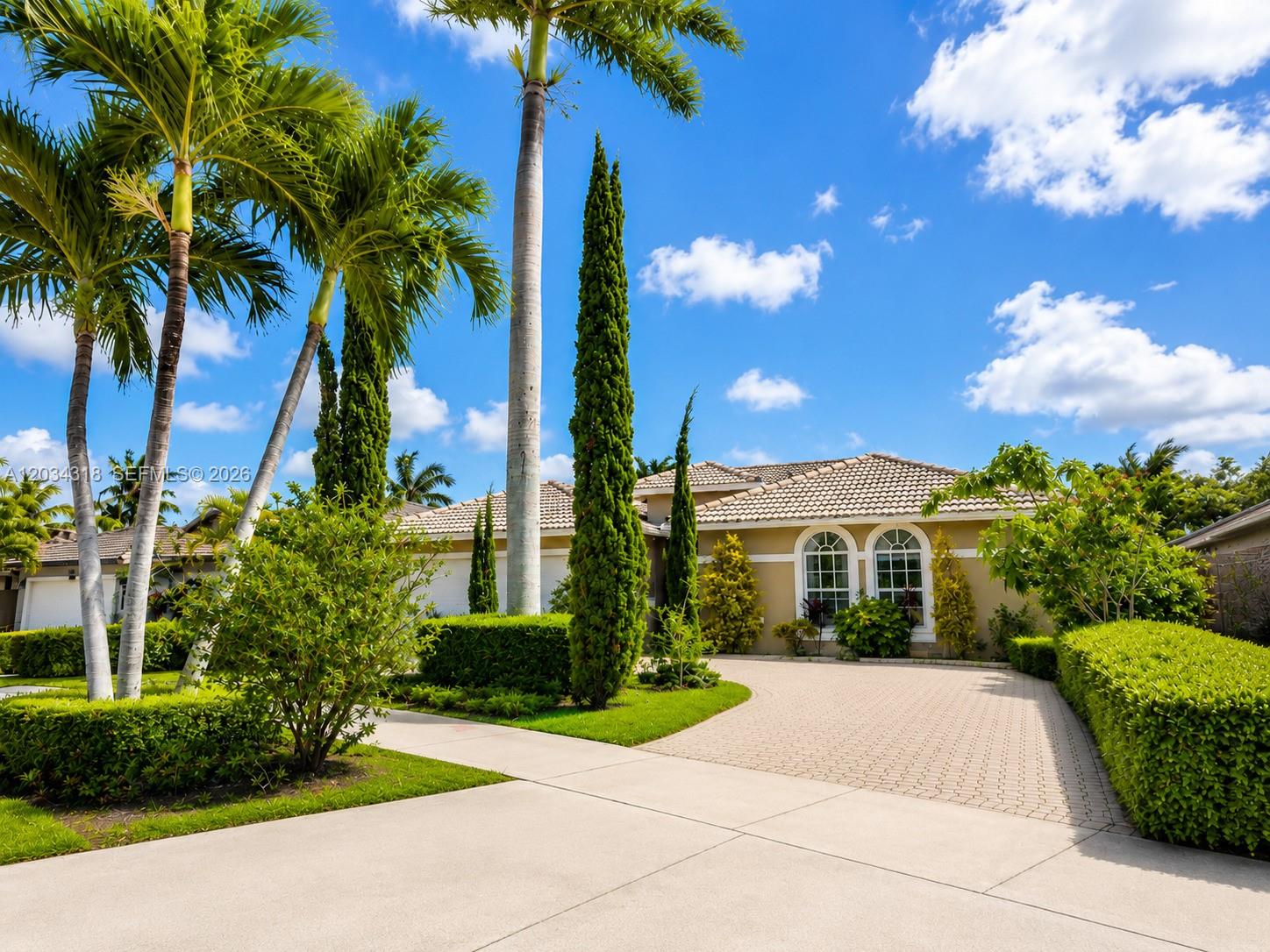 A single-story house with a paved driveway, manicured hedges, and tall palm trees — 14856 SW 179th St, Miami FL 33187, MIAMI, FL