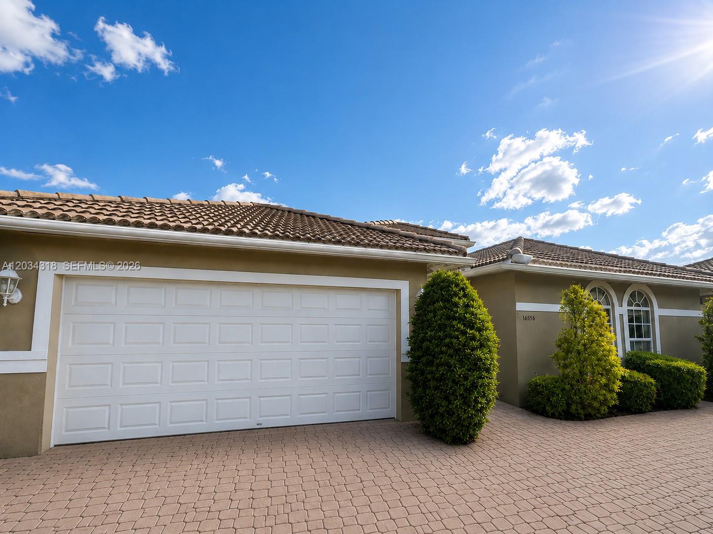 A single-story house exterior features a white garage door, tiled roof, and paved driveway — 14856 SW 179th St, Miami FL 33187, MIAMI, FL
