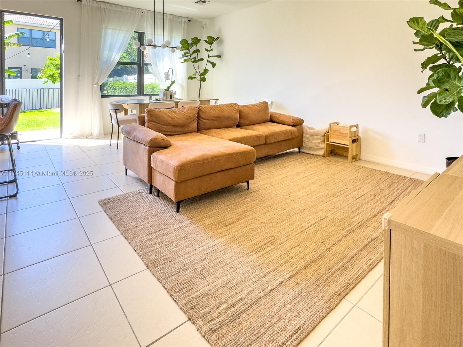A living room features a brown sectional sofa on a large rug with tiled floors — 686 NE 191st Ter, Miami FL 33179, MIAMI, FL
