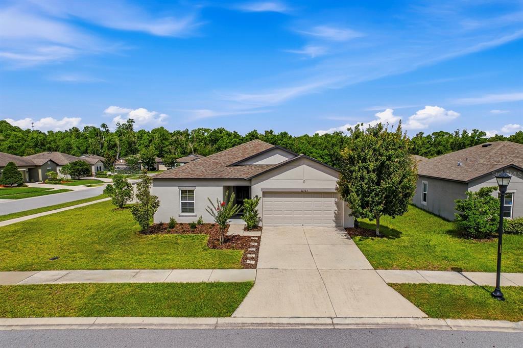A single-story suburban house with a two-car garage, light-colored stucco exterior, and a manicured lawn — 12103 GOTHIC ROAD, SPRING HILL, FL