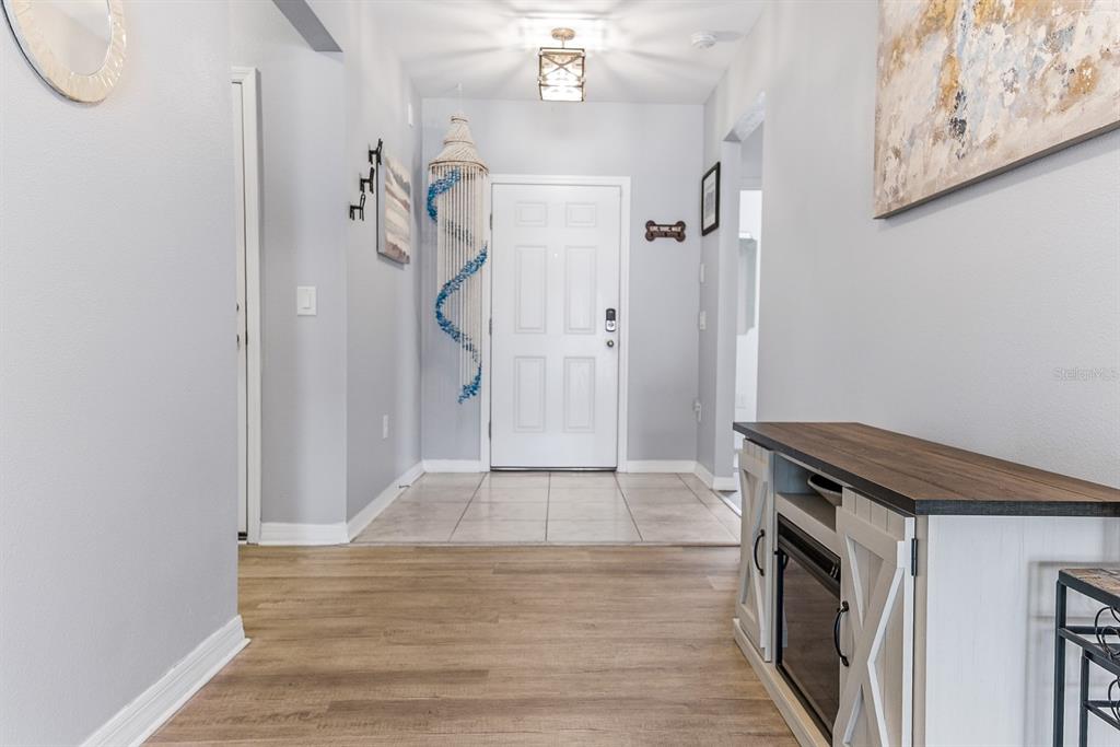 A bright entryway features light wood-look flooring, a white front door, and a console table — 12103 GOTHIC ROAD, SPRING HILL, FL