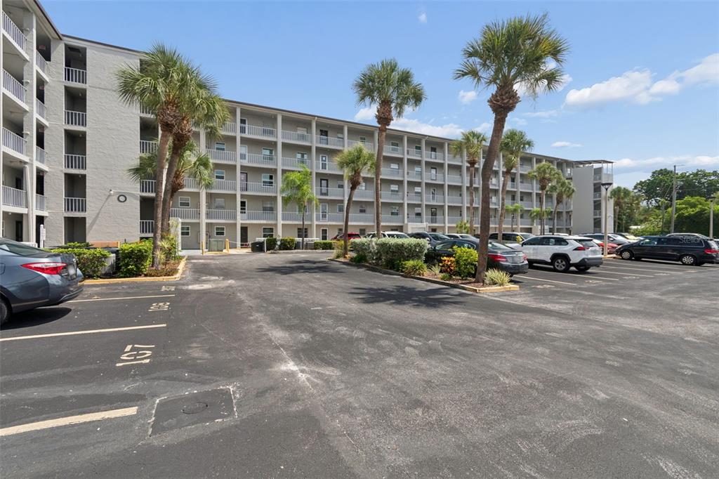 A multi-story apartment building with a parking lot and palm trees in the foreground — 3074 LAKE BAYSHORE DR UNIT O-120, BRADENTON, FL