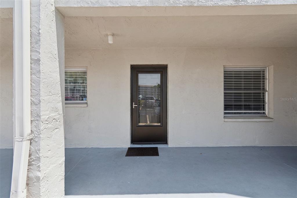 A covered entryway features a dark glass-paneled door, two windows, and a gray concrete floor — 3074 LAKE BAYSHORE DR UNIT O-120, BRADENTON, FL