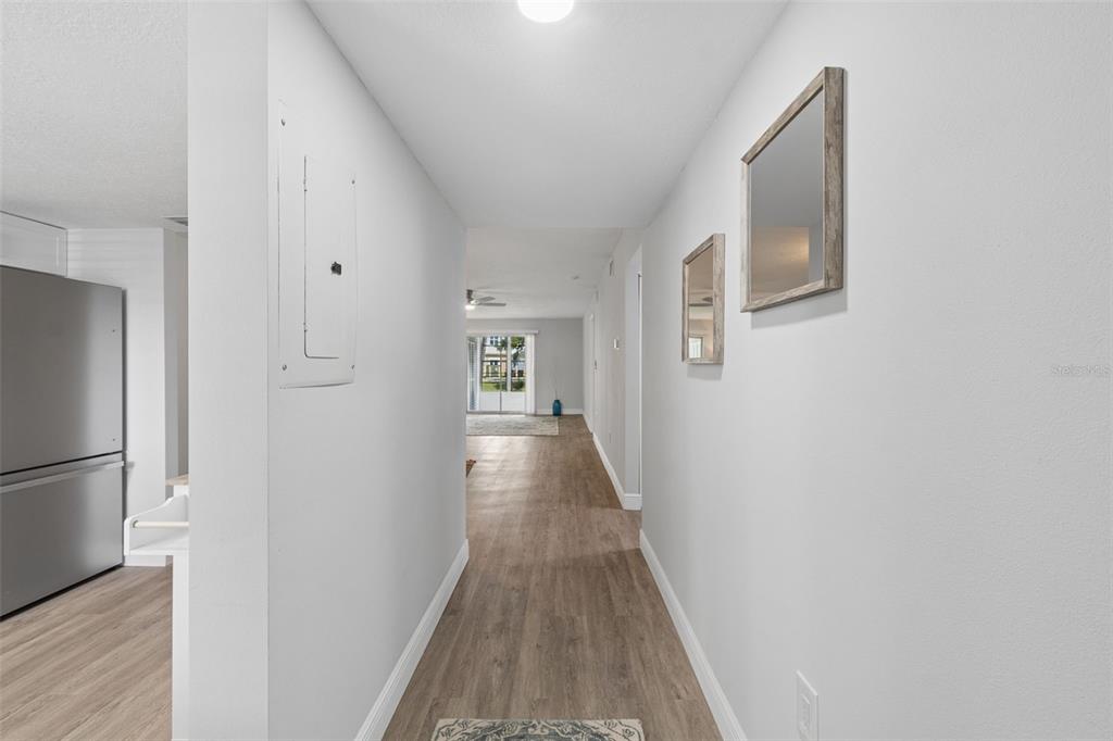 A hallway with light wood-look flooring leads from a kitchen toward a living area — 3074 LAKE BAYSHORE DR UNIT O-120, BRADENTON, FL