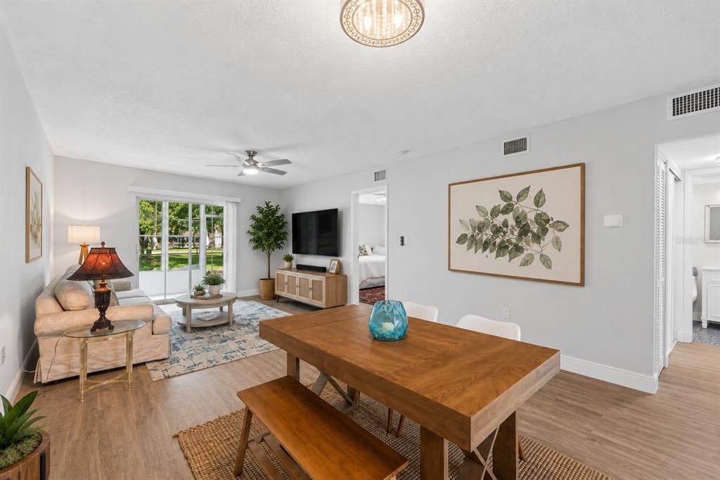 A living and dining area with light wood floors, a ceiling fan, and sliding glass doors — 3074 LAKE BAYSHORE DR UNIT O-120, BRADENTON, FL