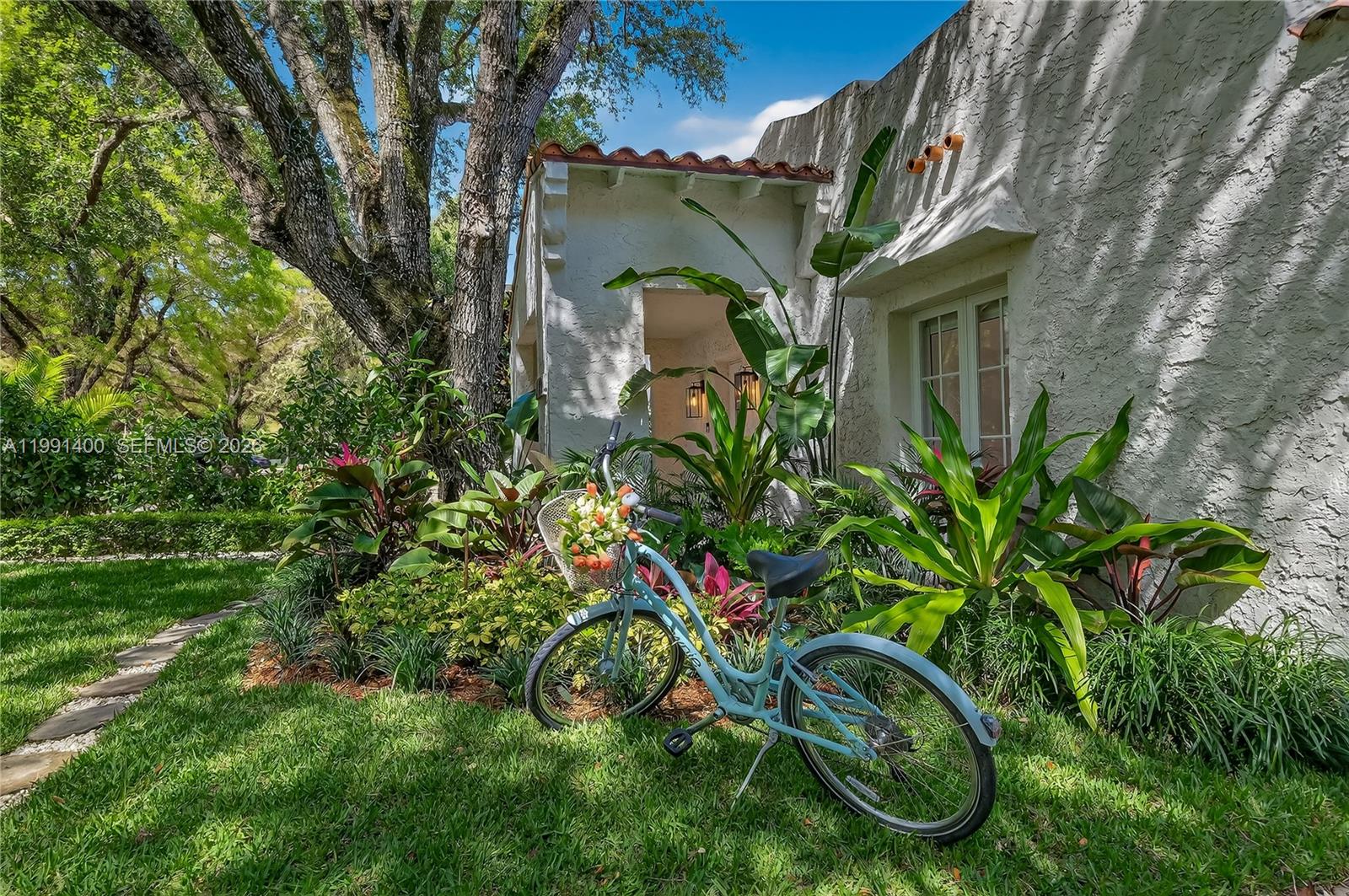 A light blue bicycle with a flower basket sits on a lawn before a house — 1109 Almeria Ave, Coral Gables FL 33134, CORAL GABLES, FL