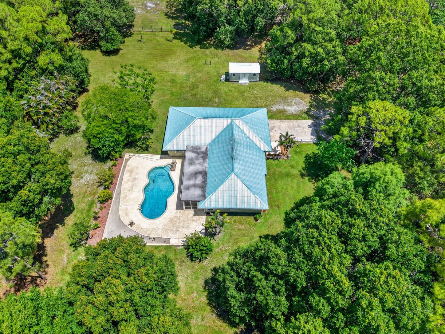 An aerial view of a house with a blue metal roof, pool, and detached shed — 15721 111th Terrace N, Jupiter FL 33478, JUPITER, FL
