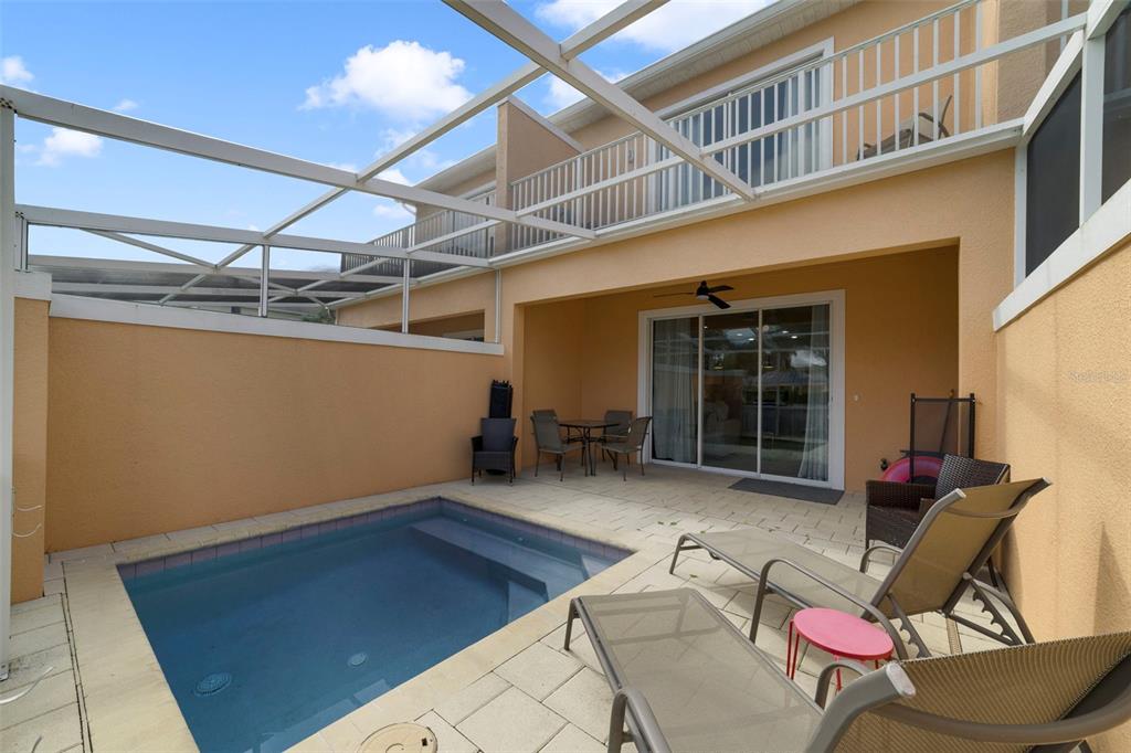 A screened-in patio features a small swimming pool, lounge chairs, and a dining set — 17349 SERENIDAD BOULEVARD, CLERMONT, FL
