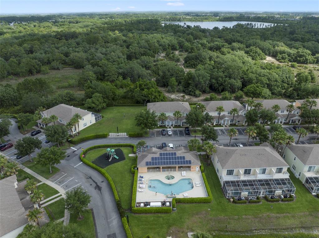 An aerial view shows a community swimming pool, playground, and surrounding residential buildings — 17349 SERENIDAD BOULEVARD, CLERMONT, FL