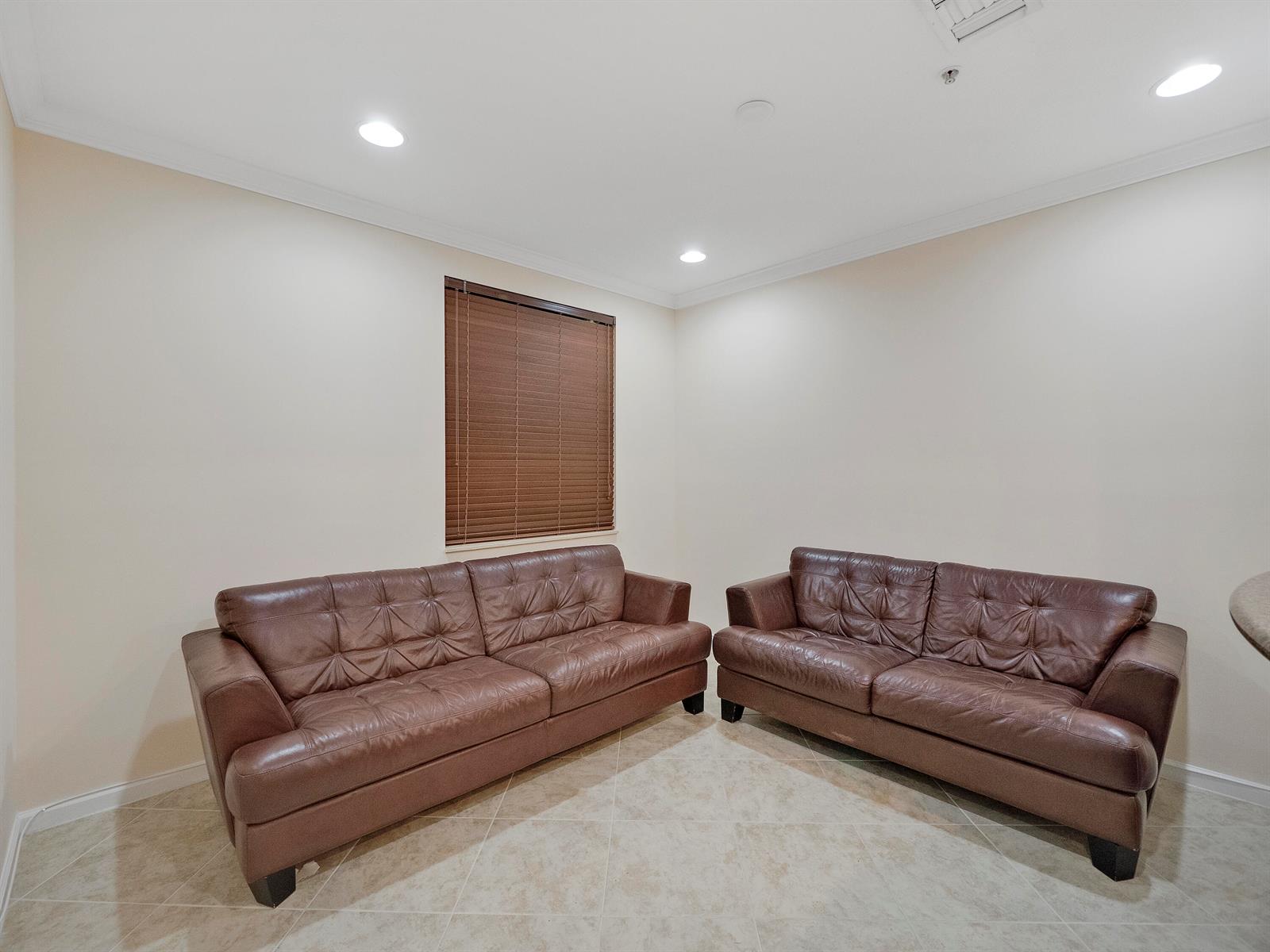 A room with beige walls, tile flooring, and two brown leather sofas — 1859 Vía Granada, Boynton Beach FL 33426, BOYNTON BEACH, FL
